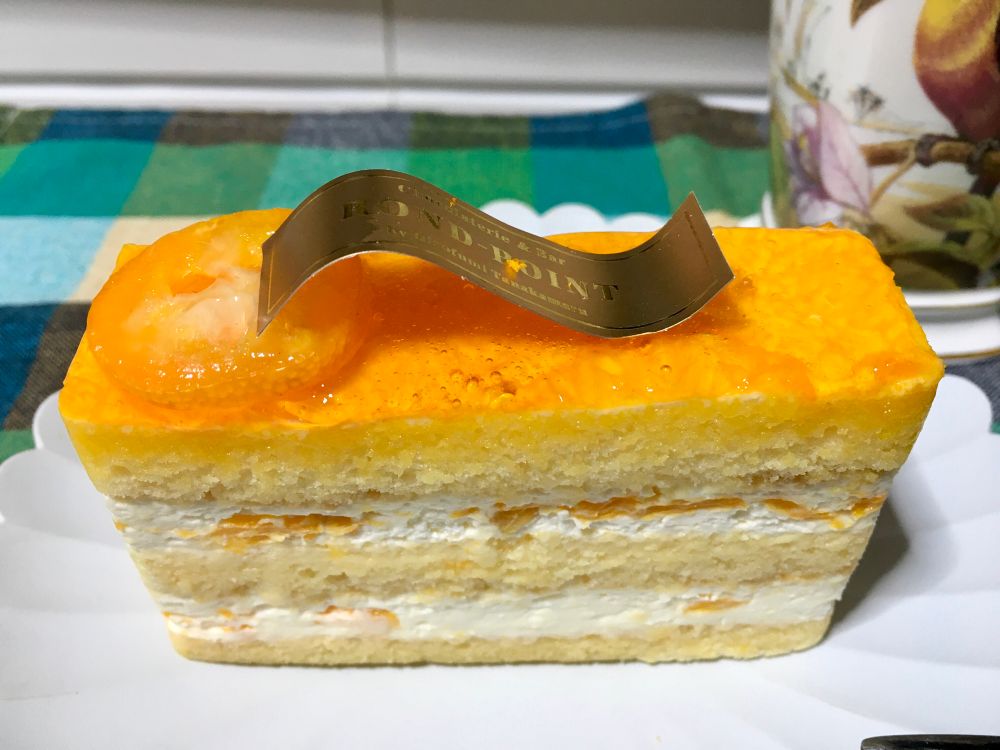 国産の柑橘類と生クリームがたっぷり挟まれている長方形の柑橘ショートケーキ　てっぺんには柑橘ジャムの層、そして輪切り金柑が飾られている