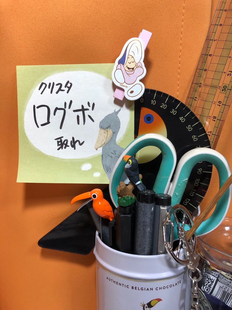 デスクの上のペン立てに「クリスタログボ取れ」と書かれたメモが貼られている