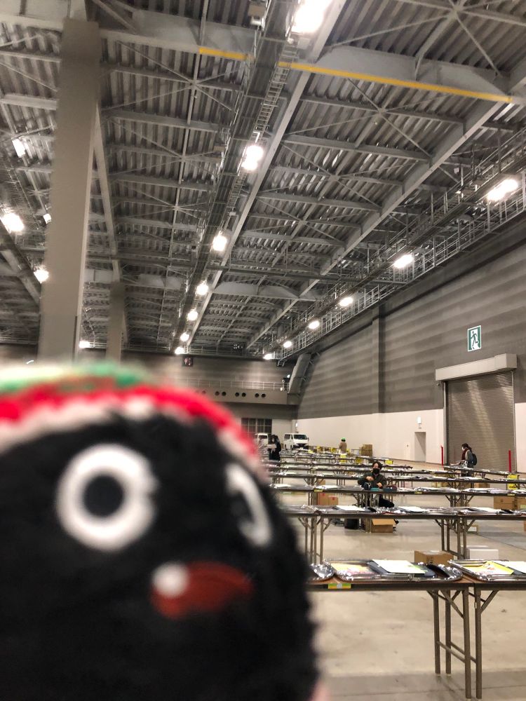 コミックマーケット開催前日、既に机が規則正しく並び、前日搬入の作業をする人がまばらにいる東ホールの中の様子