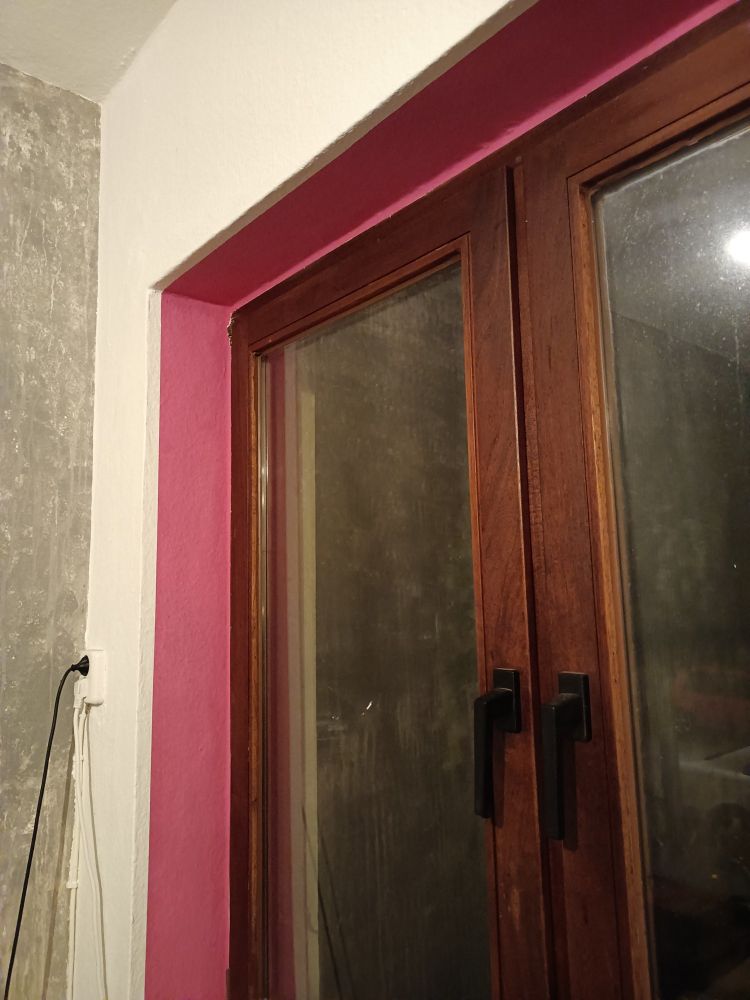 eine rosa gestrichene fensternische und ein dunkles holsfenster