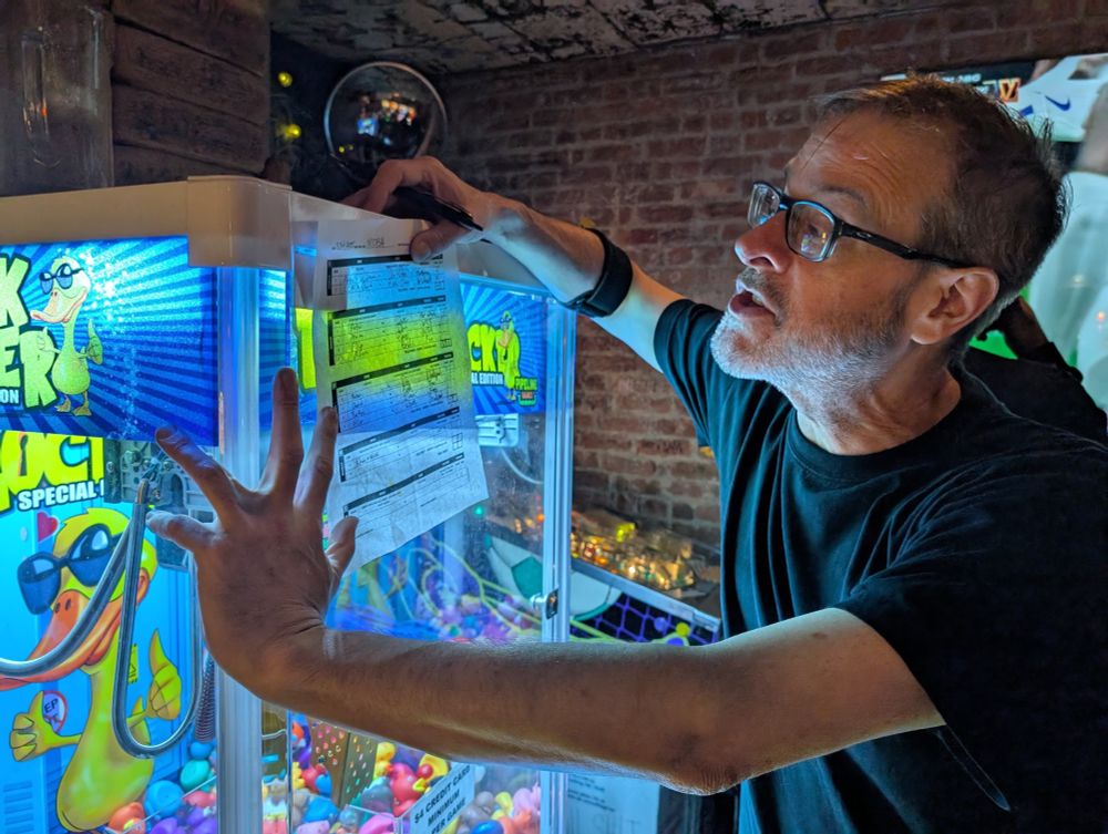 NYCFSA co-captain Erik (me) filling out the match scoresheet against a brightly lit claw machine full of multicolored rubber duckies