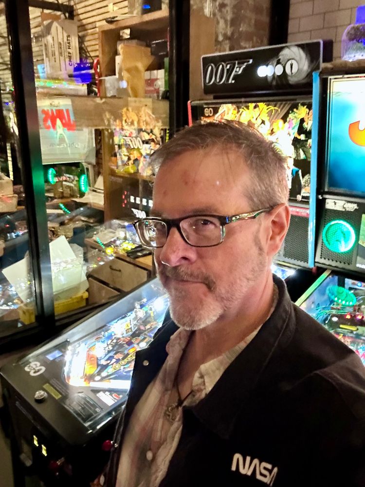 Selfie of Erik in front of pinball machines at Scrappleland