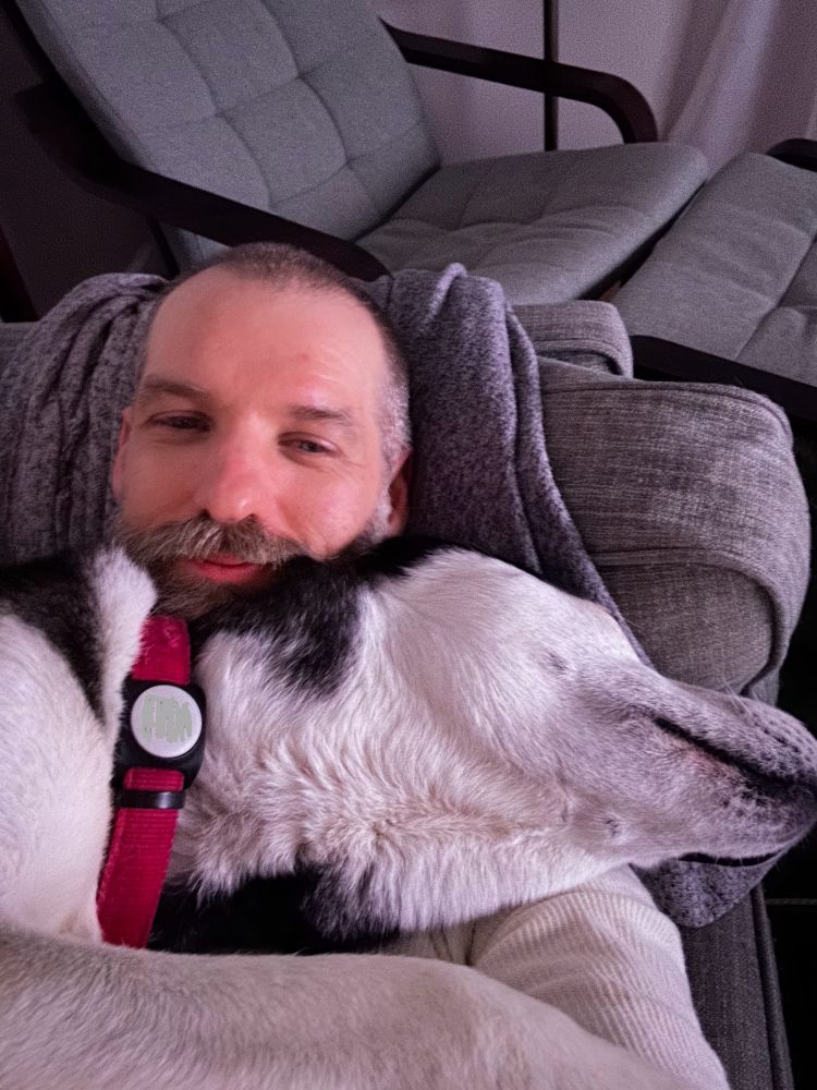 I am laying on the sofa with a siberian husky draped across me resting his head on my chest and part of my face.