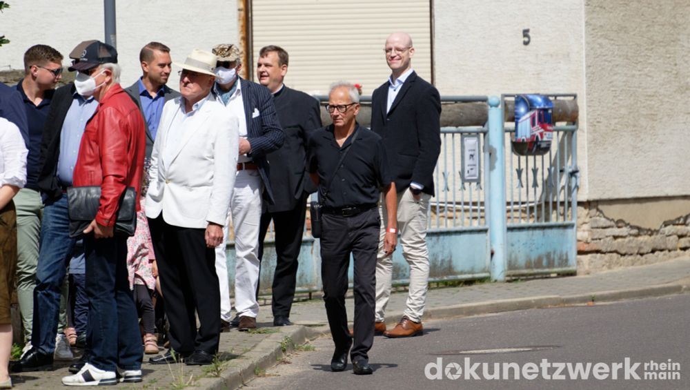 Eine Gruppe wartenden Männer vor dem Eingang zu Götz Kubitscheks IfS. Darunter der Priester neben Lukas Courtial