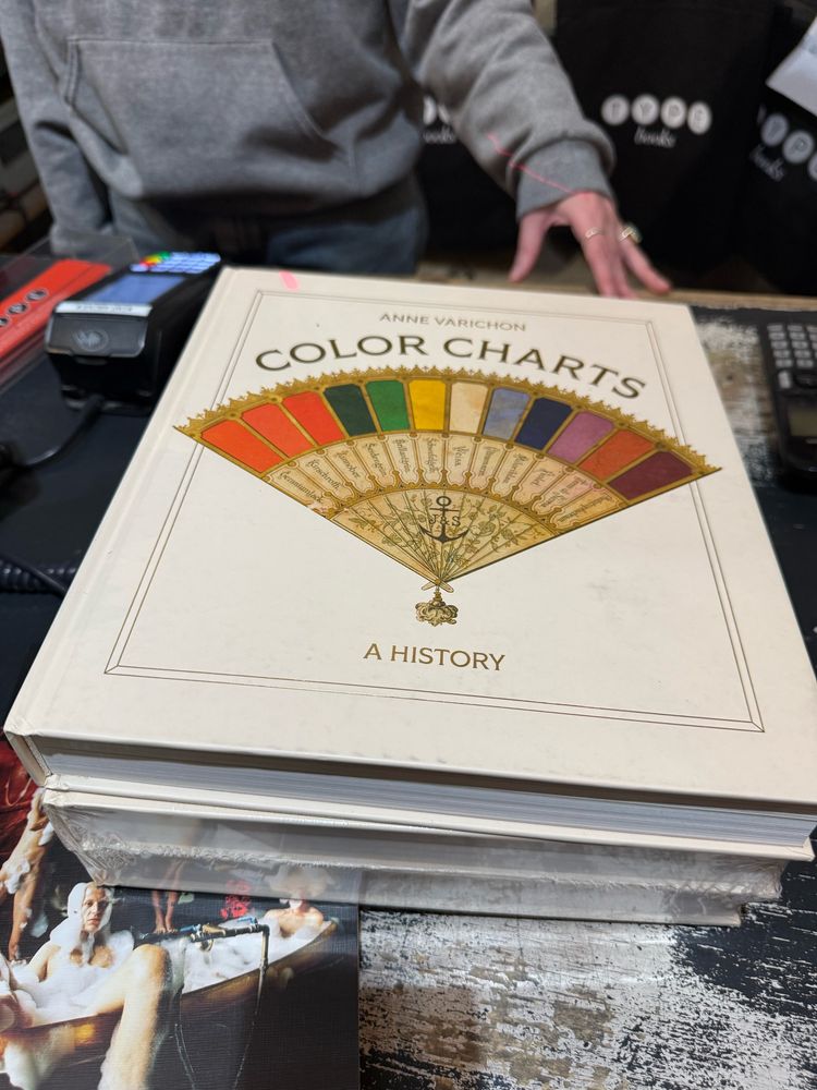 Color charts: a history, book lying on counter, salesperson’s hand behind it