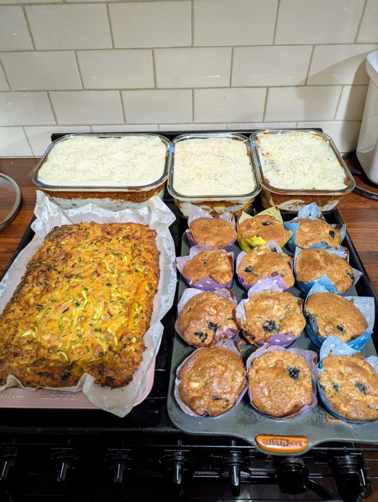 Top row is one large (four servings) portion of unbaked lasanga with two smaller portions (2 servings each). Bottom left is a large zucchini and bacon slice. Bottom right is 12 blueberry and apple muffins with speculaas seasoning