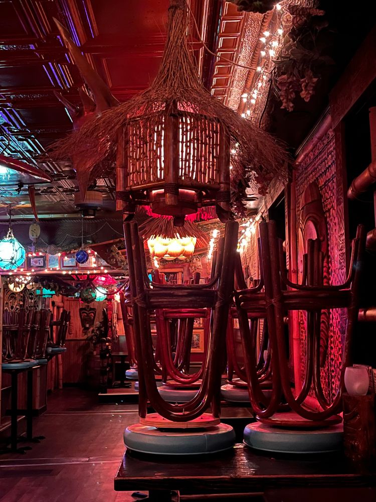 Photograph of a bar stool flipped on top of a table in a tiki bar