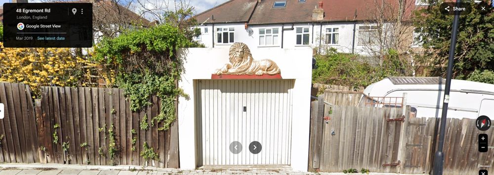 A large gold bas-relief lion over a garage, terraces and shrubbery in the background.