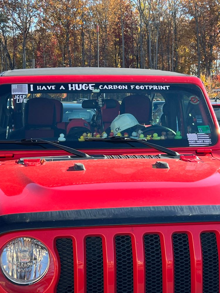 Big ole red jeep with stickers that say “I have a HUGE carbon footprint” and “fight fight fight”