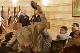 Iraqi journalist Muntadhar al-Zaidi removing his shoes and throwing them at United States president George W. Bush on December 14, 2008