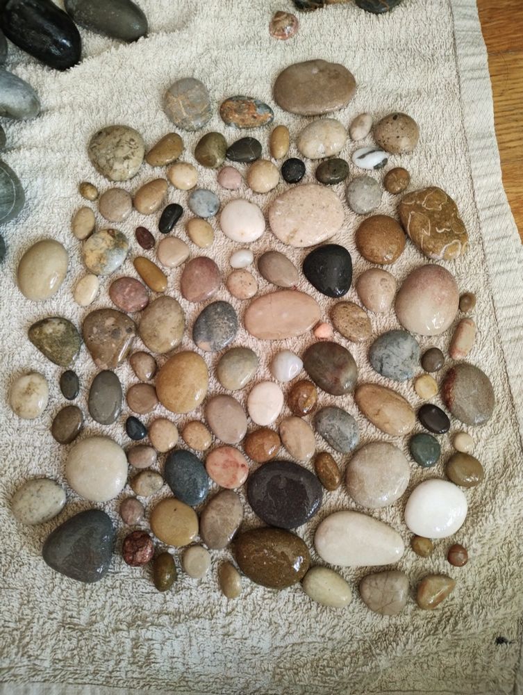A arrangement of smooth round and oval beach stones on a beige towel 