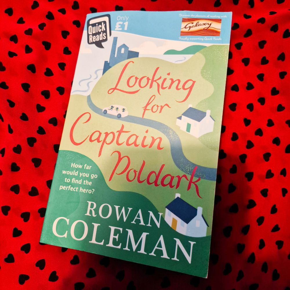 A copy of Looking for Captain Poldark by Rowan Coleman on a background of red fabric with black hearts on it