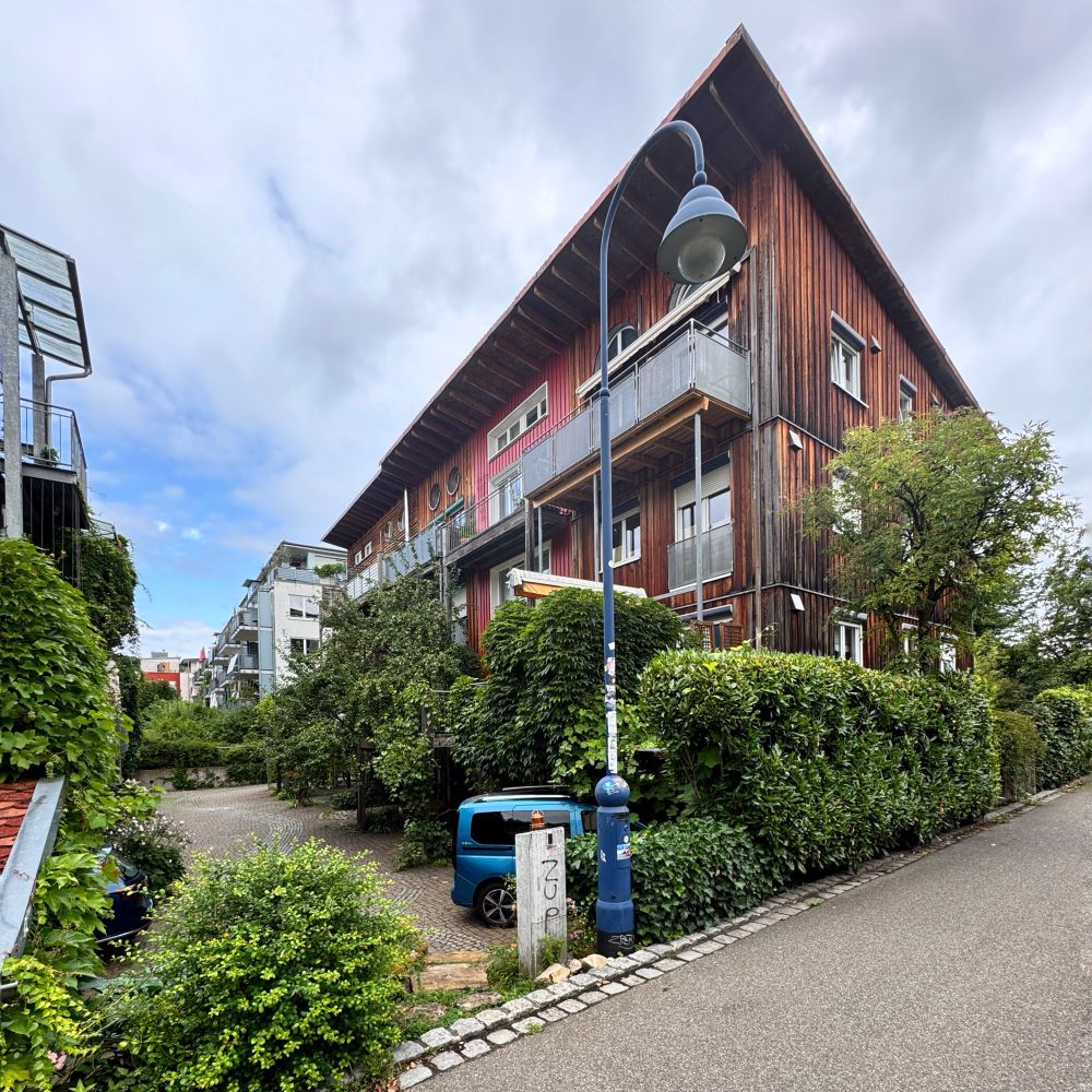 A street scene from Vauban showing back to back apartments, with green front gardens hiding the cars