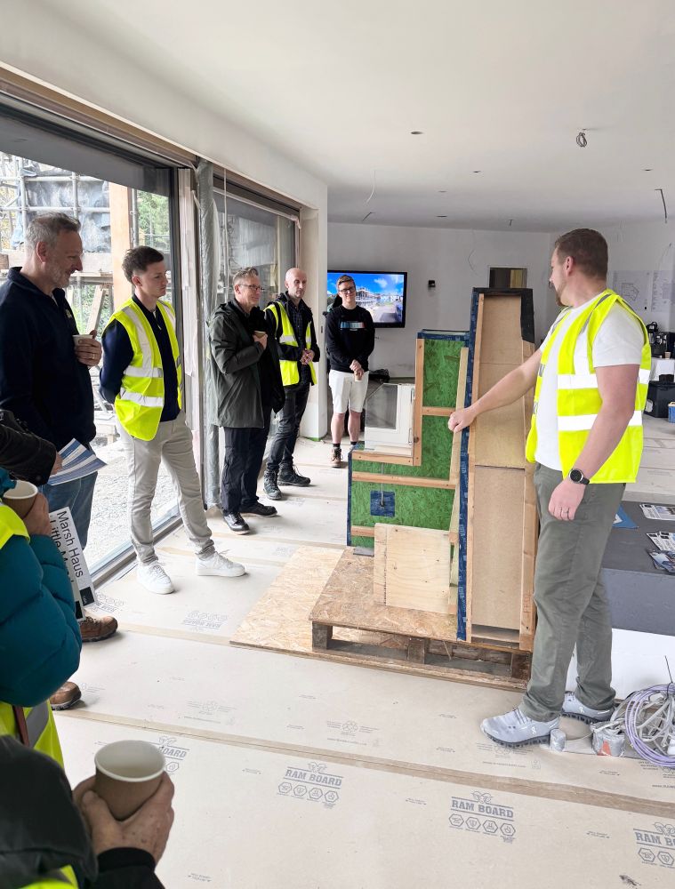 Visitors to Malvern passivhaus during open day, discussing high performance wall assembly 