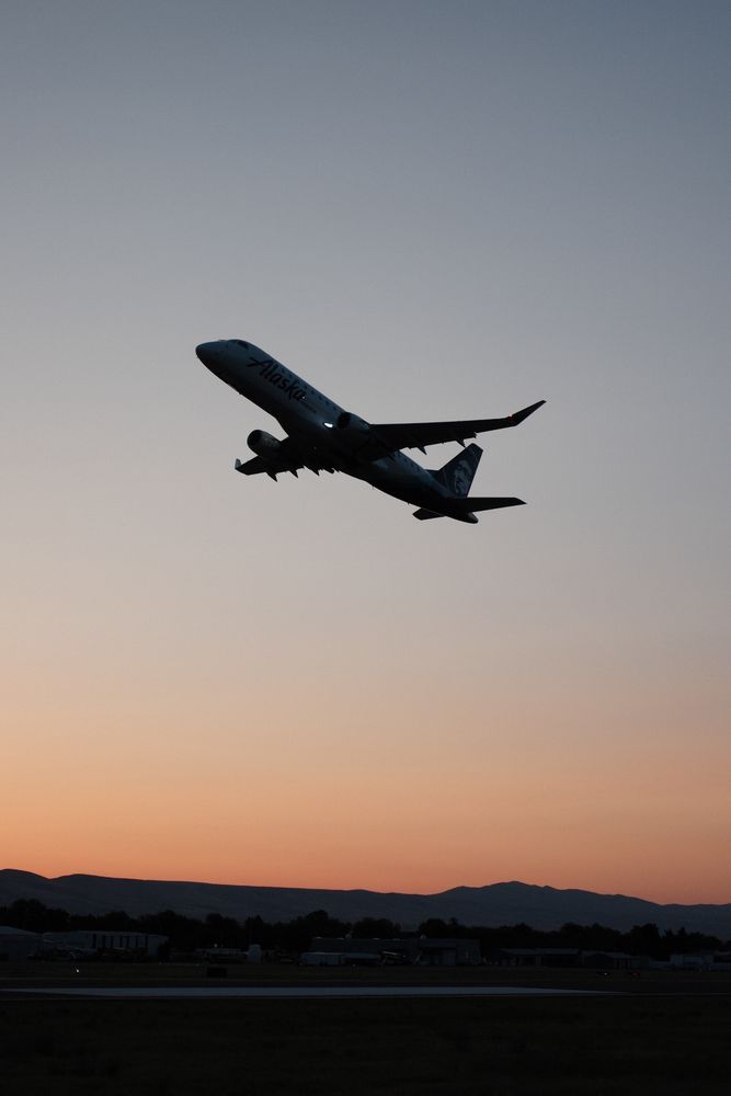 Silhouette of an Embraer taking off in front of the sunrise. 