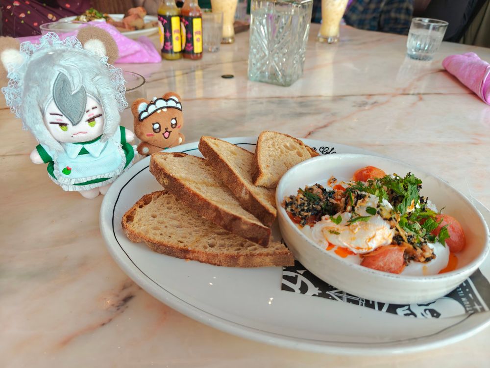 rei and eiden pose next to a plate of turkish eggs and levain bread slices