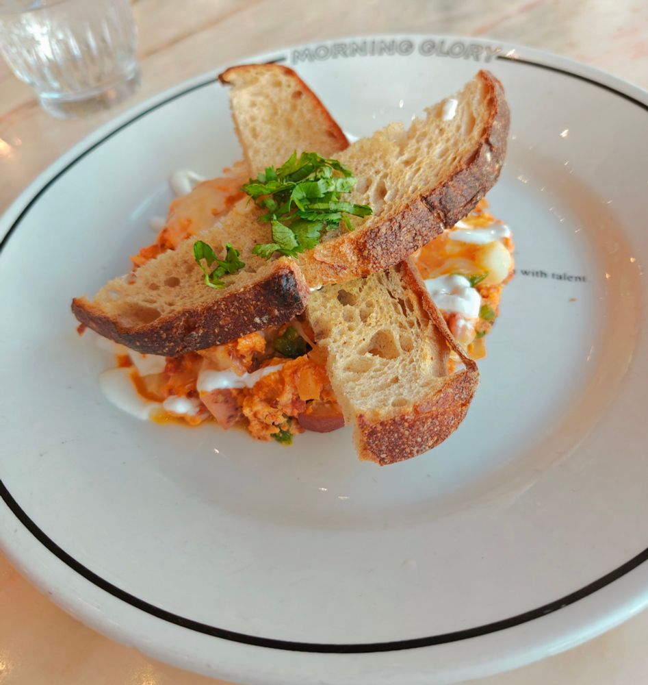 two slices of toast placed crossed on a hash of chorizo, eggs, and potato