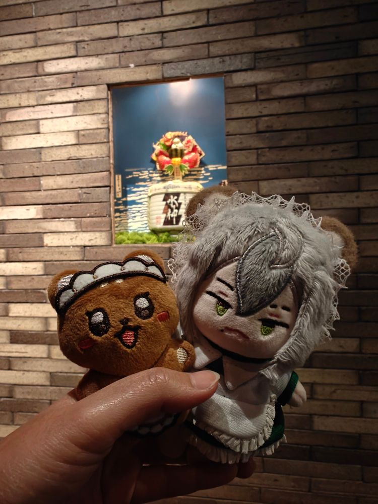 eiden and rei pose in front of a display drum of sake
