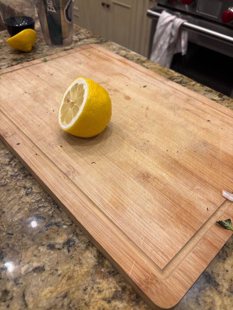picture of a dirty wood block cutting board with half a lemon on it