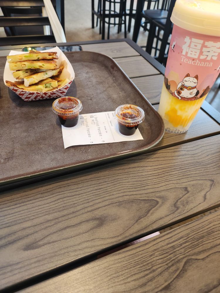 A picture of seafood pancakes with some sauce included alongside a mango smoothie with crystal boba pearls.