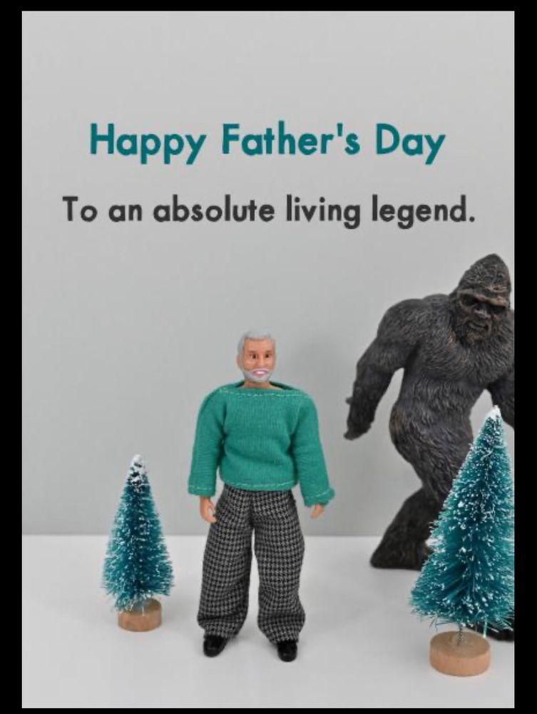 Father’s Day Card with a male doll in green sweater and checked pants standing between two toy evergreen trees and a Bigfoot toy in the background. It reads ‘happy Father’s Day to an absolute living legend’. 
