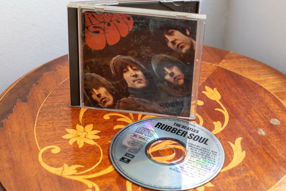 CD “Rubber Soul” dos Beatles ao lado de sua caixinha plastica sobre uma mesinha