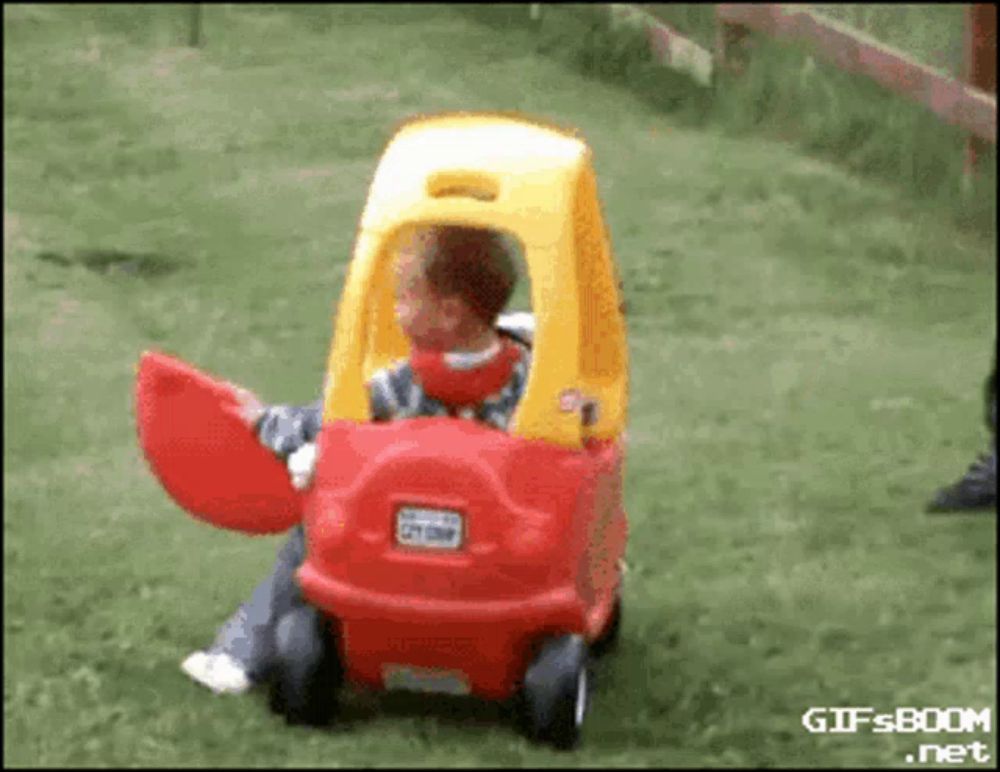 a child is sitting in a red and yellow cozy coupe toy car with the doors open