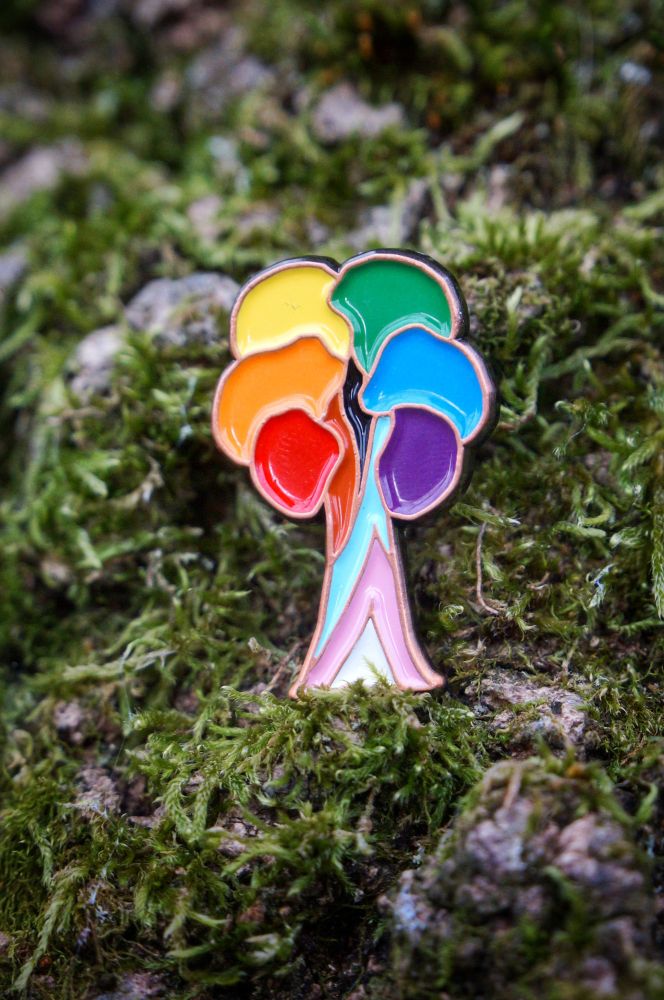Enamel pin in the shape of a tree with progress pride flag colours