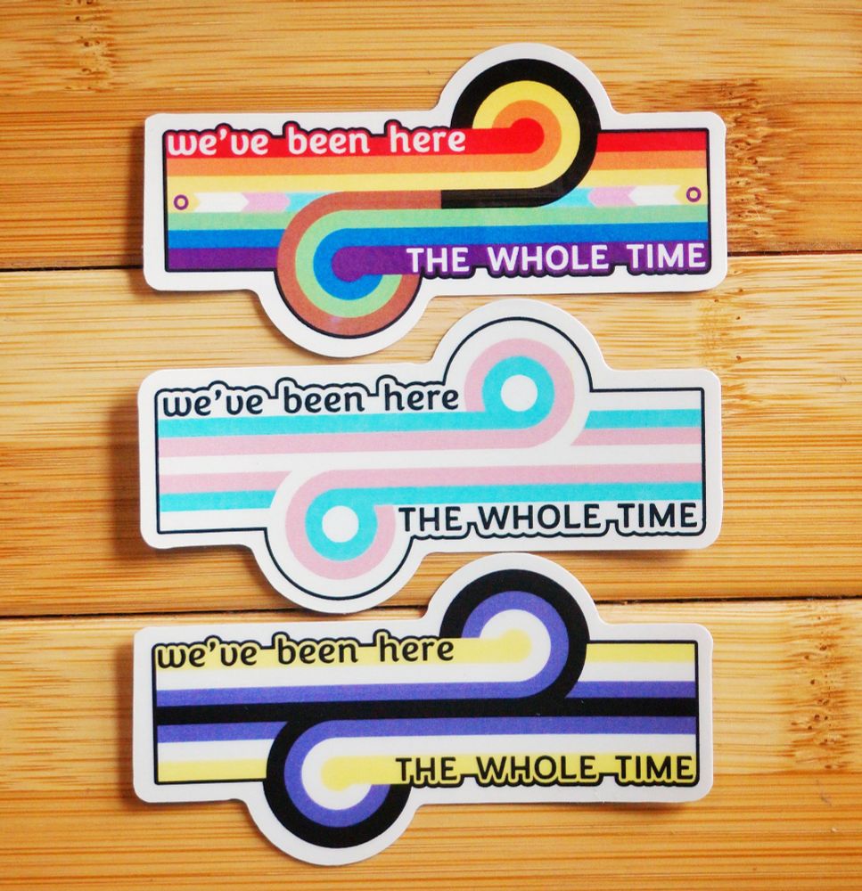 Three vinyl stickers of the game changer loop-de-loop in progress pride, trans, and non-binary colours respectively. The stickers also have the words 