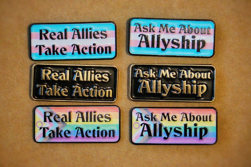 Rectangular pins with rounded corners and text that reads "ask me about allyship" or "Real allies take action" on the trans pride flag, intersex inclusive progress pride flag, and a plain black background.