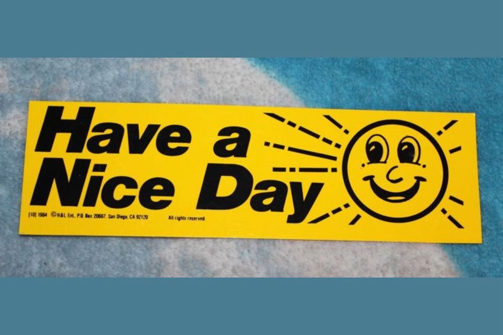 Vintage bumper sticker that is yellow and says “Have a Nice Day” with a smiley sun to the right 