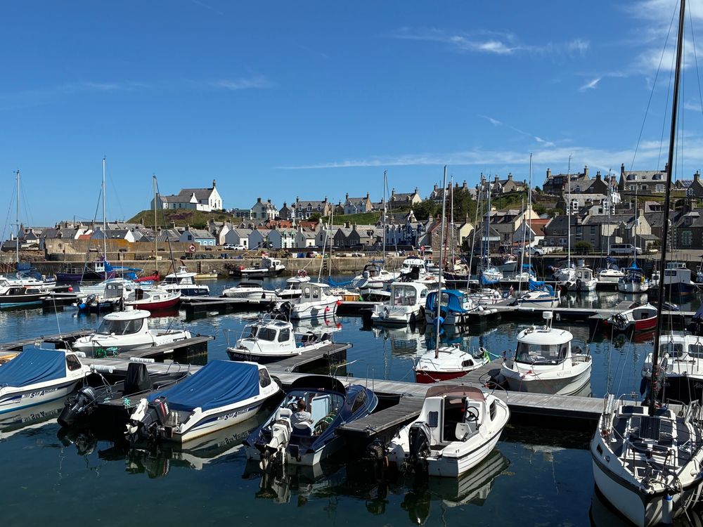 The small harbor seen from bottom of last of three visible (and total) pontoons. The eastern inner seawall in background, along with a small white church on the headland. Indigo center back behind many other small boats.