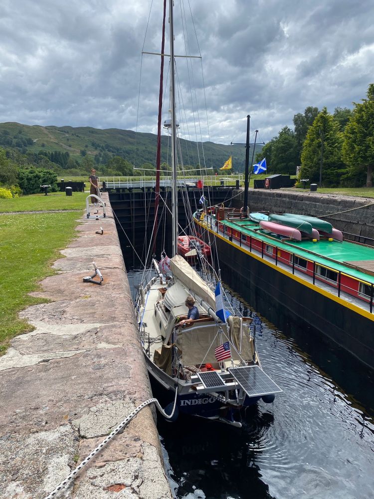 Indigo locking into Loch Oich. She shares the lock with a big green and black barge to starboard.