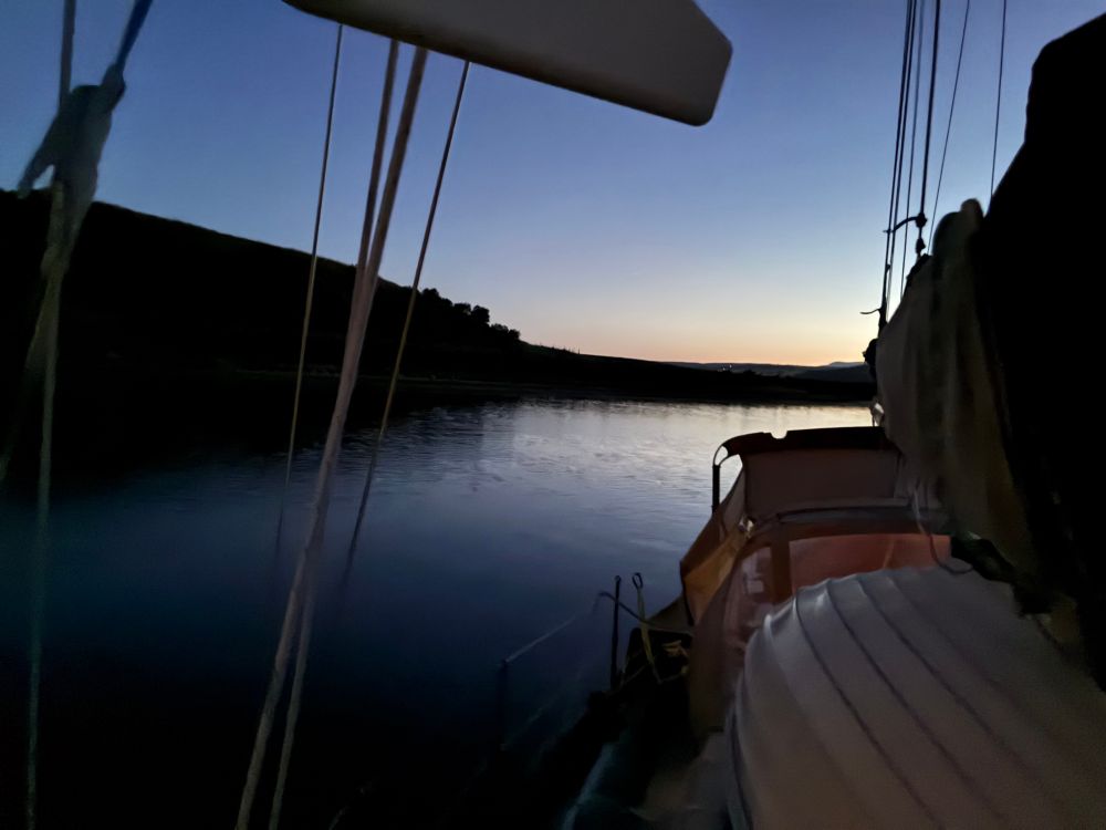 Looking astern from Indigo at her anchorage. The shore is rather close and the very last embers of sunset are visible over the northern highlands.