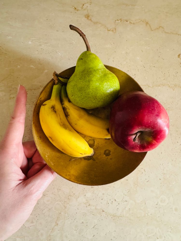 A bowl of fruit including two tiny bananas shorter than the finger I’m holding up next to them. I have medium-sized hands for an adult.