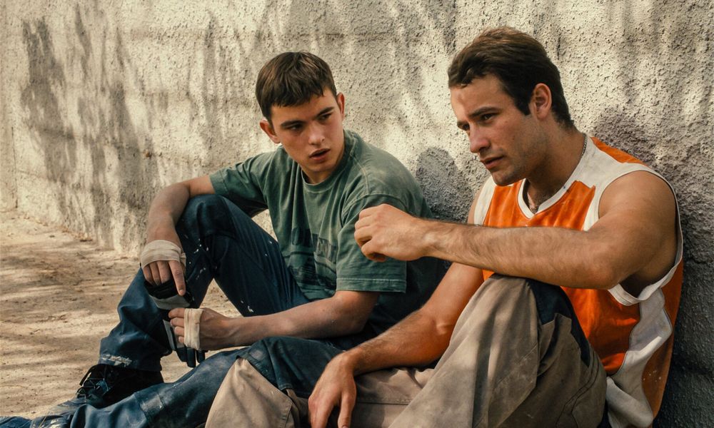 screen du film : deux hommes blancs (même si l'un d'origine plutôt française et l'autre ukrainiens) assis contre un mur au soleil. L'un à l'air plus vieux et mature que l'autre, ils se parlent