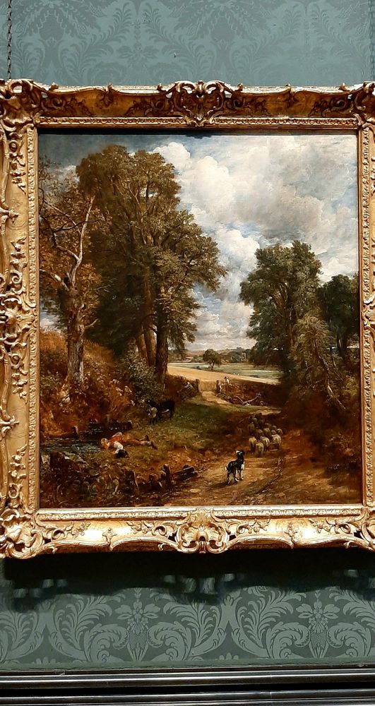 A lane leading from East Bergholt toward Dedham, Essex, depicts a young shepherd boy drinking from a pool as the summer heat rises, clouds mull overhead and the dark trees loom above Fen Lane. The boy's dog waits impatiently, wanting to get on and chase the sheep into the cornfield beyond the cutting. There is a gate there into the golden cornfield.