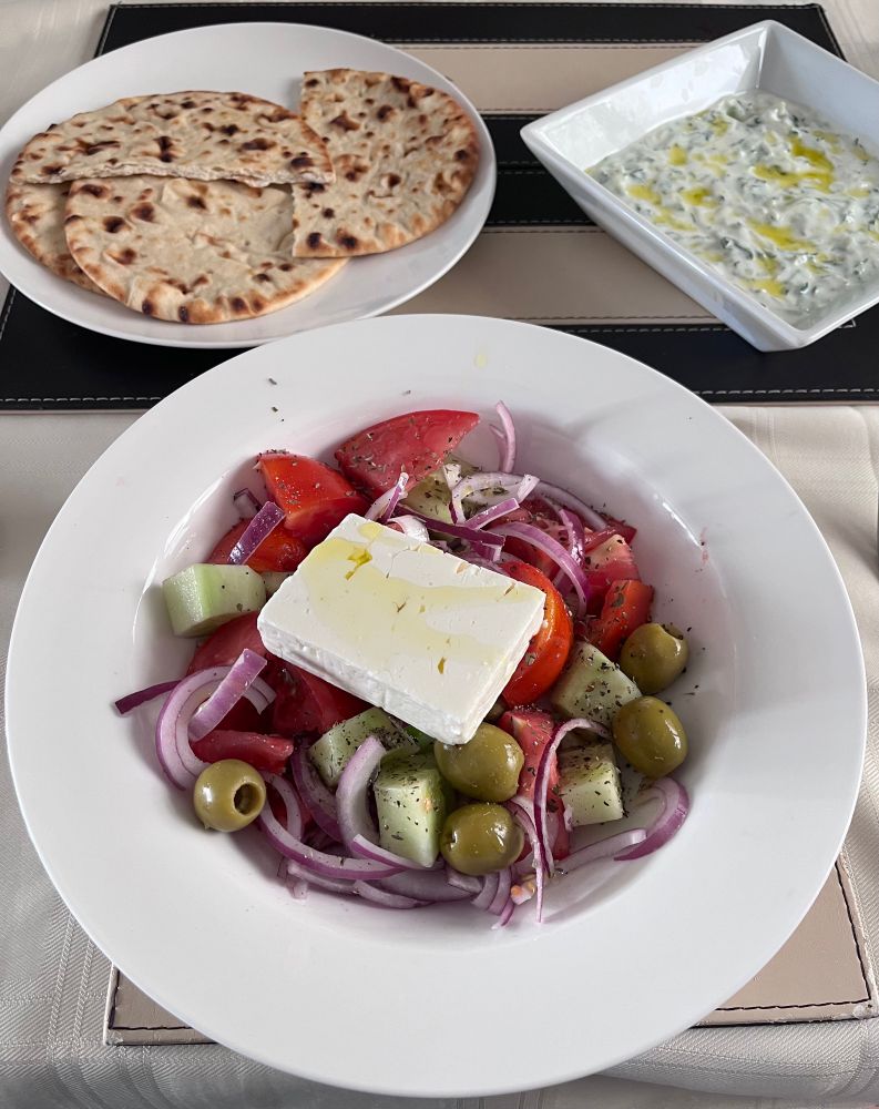 Traditional Greek salad, Greek flatbread and dish of homemade Tzatziki sauce 