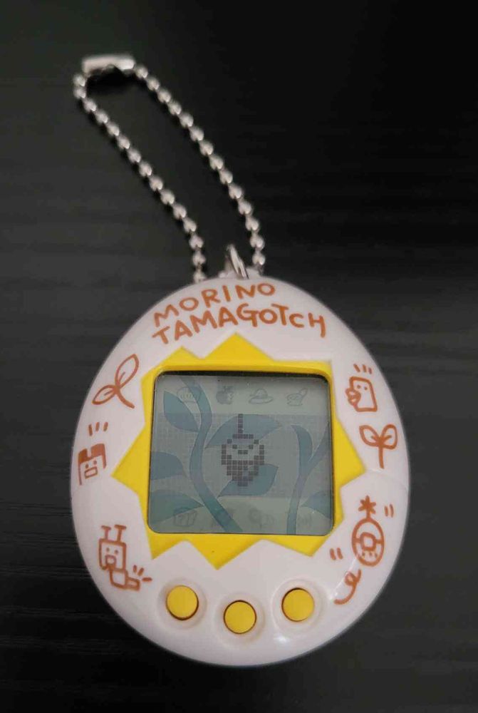A white shell Mori de Hakken! Tamagotchi, with Minotchi displayed onscreen.