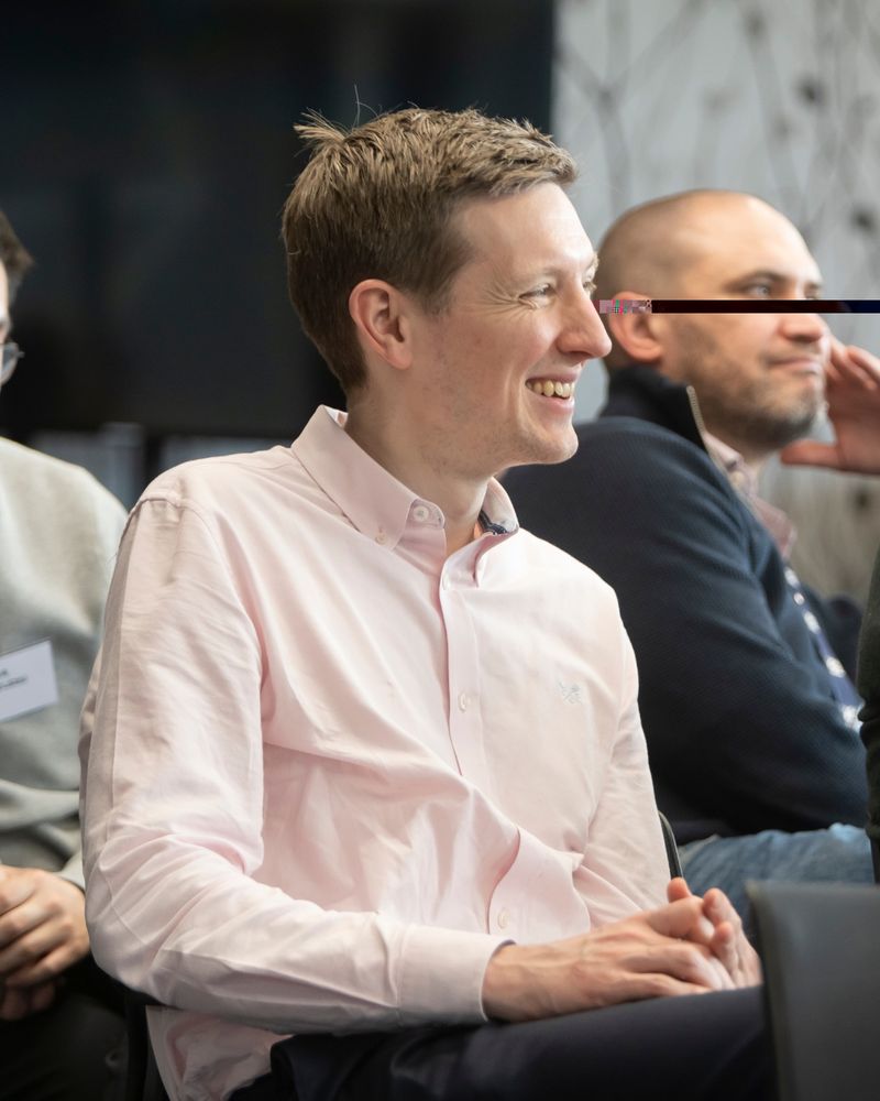 man in pink shirt listens to a talk