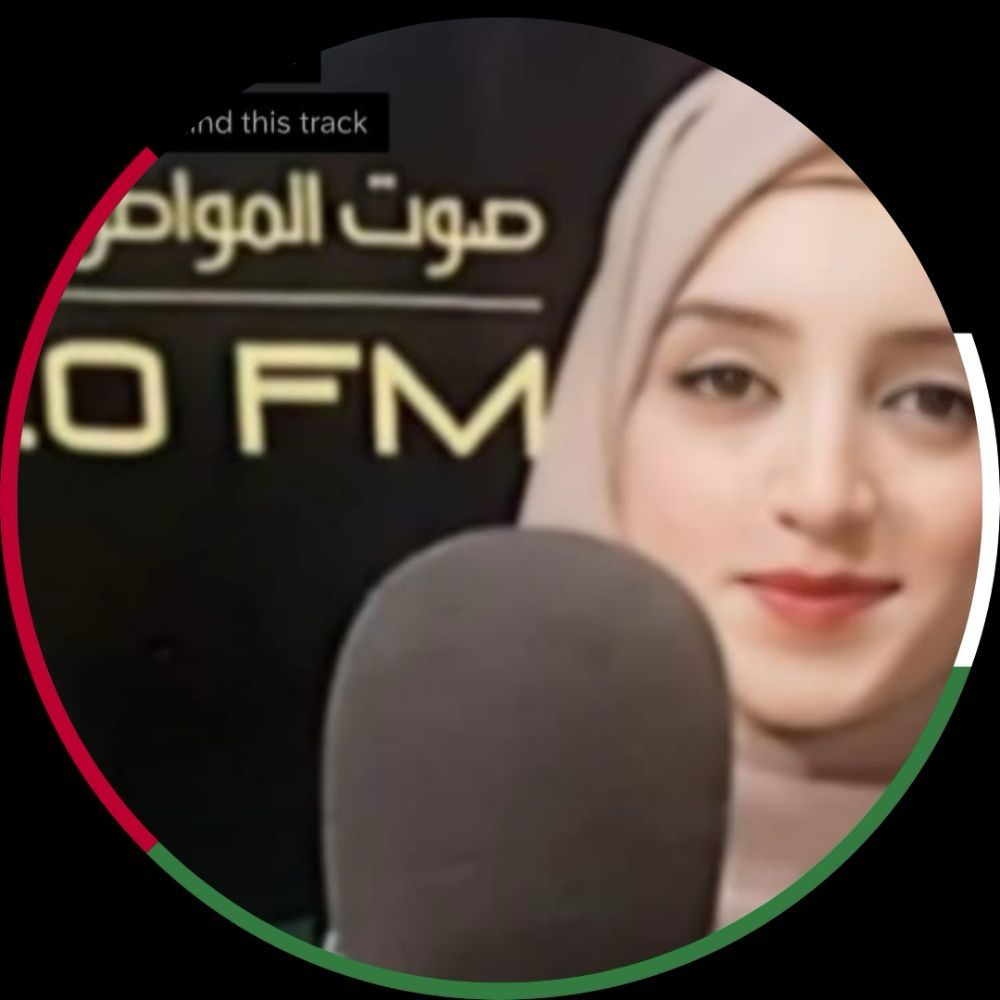 A photo of Fidaa Umar, She smiles softly and she has a microphone in front of her.