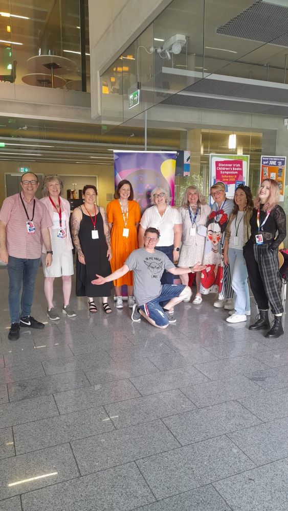 Nine people standing in a line, one person is in front of them crouching