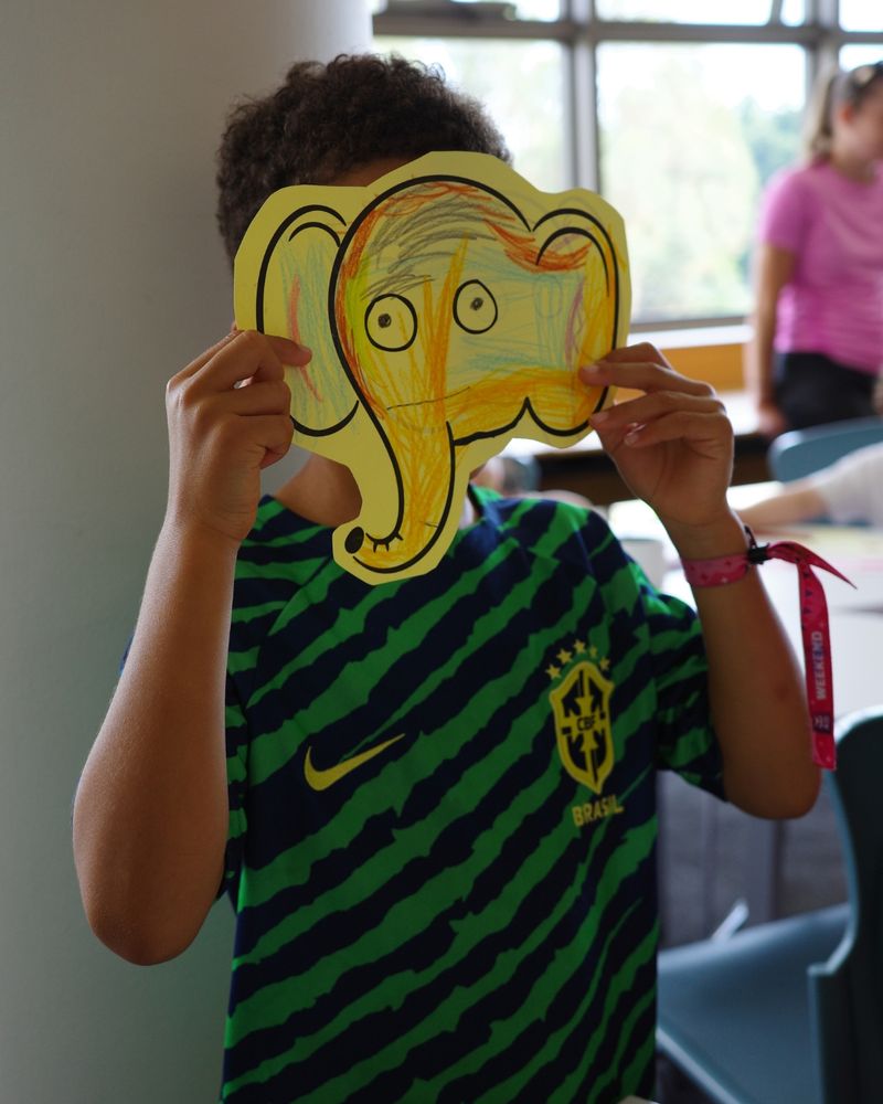 a child with a colourful elephant face mask held up over their face