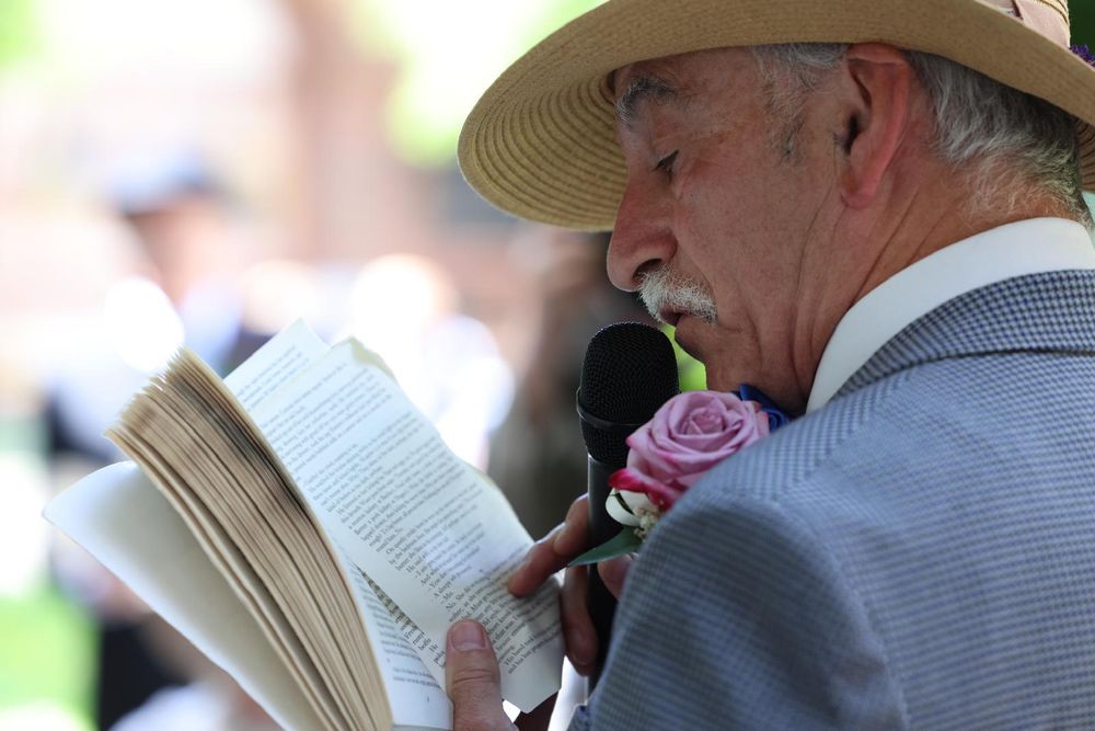 A man reading from a book speaking into a microphone