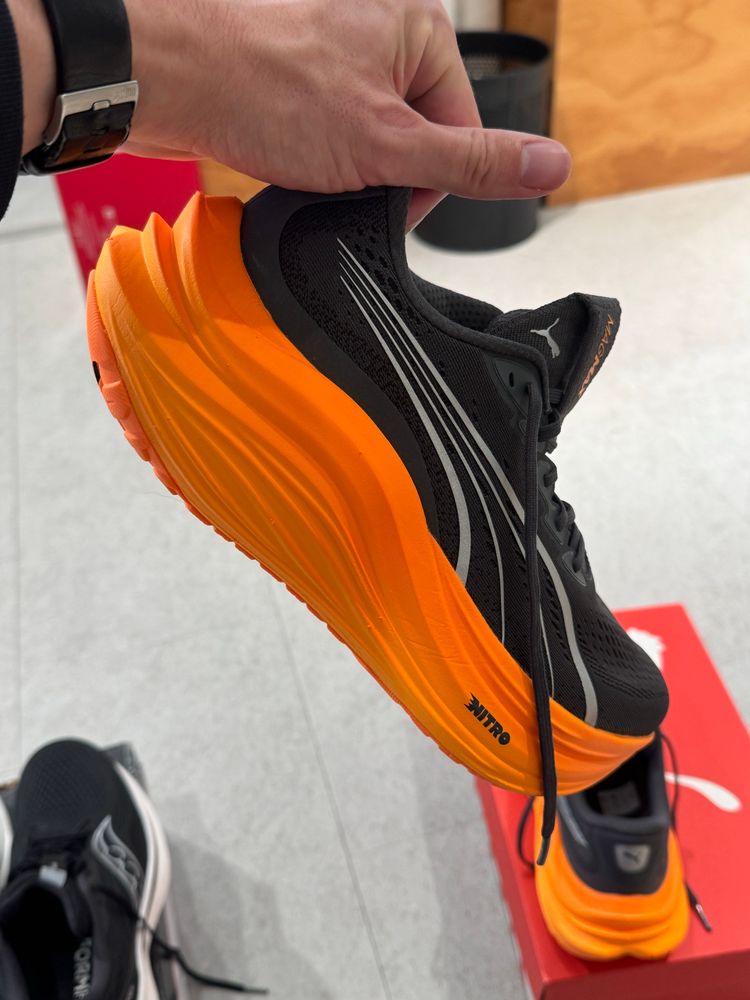 A pair of Puma running shoes, I’m holding one in my hand, it’s grey and has got a super thick orange sole. 