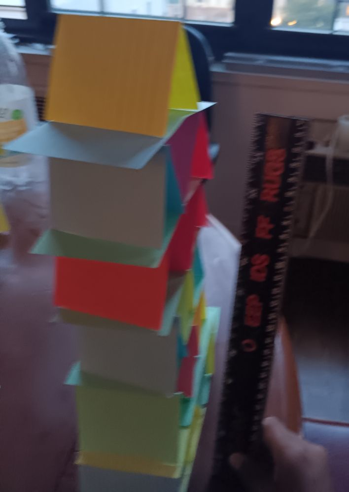 A fuzzy pic of a tower built of index cards next to a ruler

