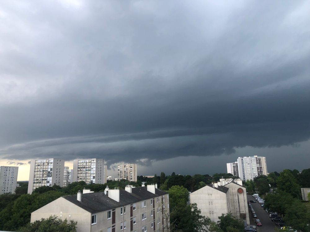 Vue d’une super cellule orageuse avec un nuage d’arcus bien dessiné au dessus de barres d’immeubles 