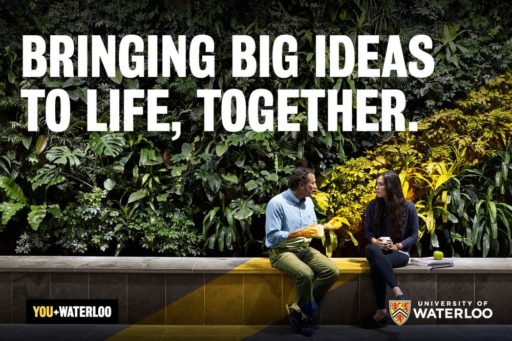 Employees meeting in front of a living wall with the phrase, "Bringing big ideas to life, together. You + Waterloo." 