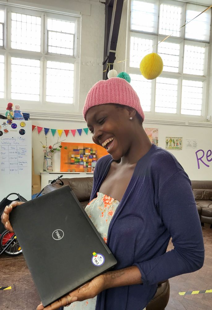 A woman smiling holding a laptop