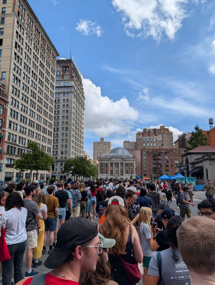 A crowd of people waiting for the Zohran Mamdani scavenger hunt in front of Tammany Hall in Union Square
